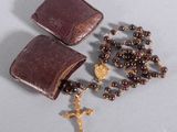 rosary and leather case with gold cross on grey background