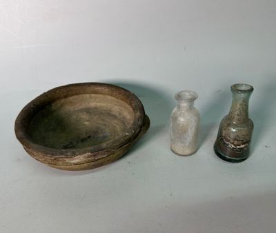three small glass bottles and a wooden bowl on a table