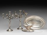 trois bougeoirs en argent et une assiette ornée d'un oiseau