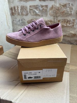 purple sued sneakers with laces on top of a cardboard box