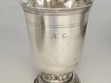 une coupe ancienne en argent posée sur un socle, sur fond blanc