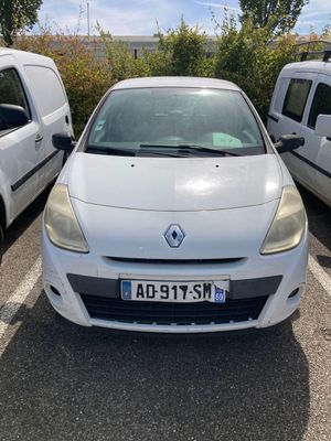 La voiture blanche est garée sur le parking, à côté de la camionnette blanche.