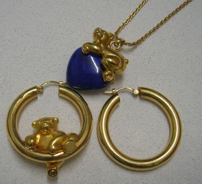 un collier en or orné d'un cœur bleu et d'un ours en peluche en or
