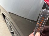 a person holding a ruler in front of a car