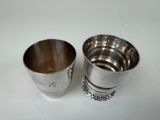 two silver cups sitting on top of a table next to each other