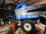a blue and yellow new holland combiner parked in a barn