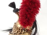 un chapeau orné de plumes rouges posé sur un casque à imprimé léopard