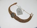 un bracelet en or sur lequel est fixée une montre, avec une étiquette de prix