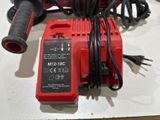 a red corded drill with a charger attached to it