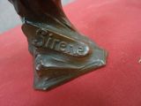 une statue en bronze représentant un homme assis sur un coussin rouge