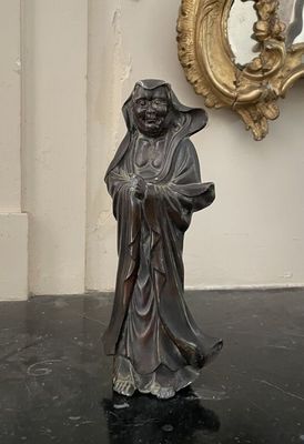 une statue représentant un homme tenant une canne devant un miroir