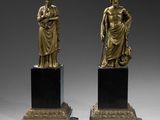 une paire de statues en bronze représentant une femme et un homme, posées sur des socles en marbre