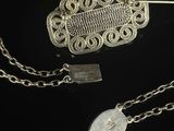 a close up of a silver broochle with a chain around it