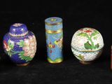 Plusieurs vases de différentes couleurs sont alignés sur une surface noire