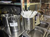 a lot of utensils in a metal cup on the counter