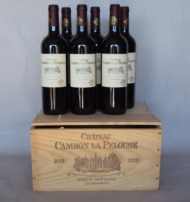 quatre bouteilles de vin se trouvent dans une caisse en bois posée sur une table