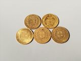 four gold coins are arranged on top of each other on a white surface