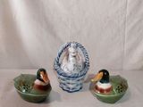 trois canards en céramique posés sur une table, à côté d'un panier