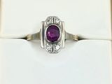 une photo d'une bague sertie d'une pierre violette, présentée dans un écrin blanc