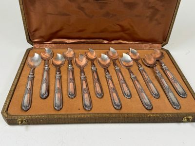 six cuillères dans un étui, posées sur une table