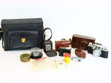 a black bag with a camera, a camera case, a camera and other items on it