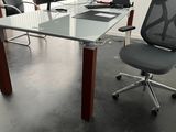 un bureau en verre sur lequel se trouvent une chaise et un ordinateur