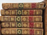 several old books stacked on top of each other on a white surface