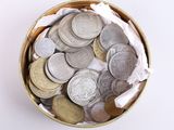 a small metal container filled with coins on a white surface