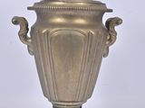 a large metal vase with a lid on a stand