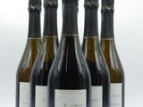 six bottles of wine are lined up in a row on a white surface