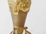 a gold vase on a stand on a white surface