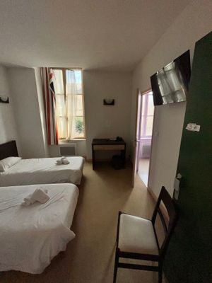une chambre avec deux lits, une télévision et un fauteuil