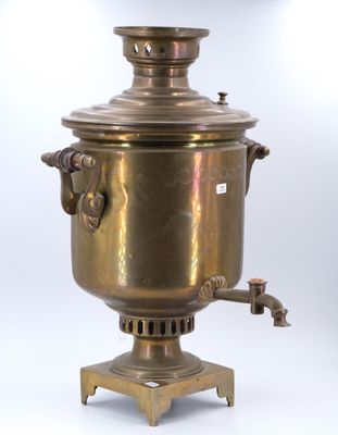 une bouilloire ancienne en laiton posée sur un support, sur fond blanc