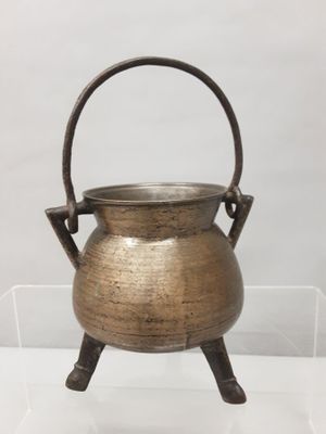 an old brass cauld with a handle on a stand