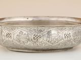 an old silver bowl with ornate designs on it on a white surface
