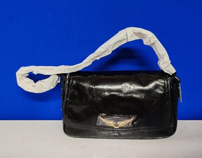 un sac à main noir avec une anse blanche posé sur une table