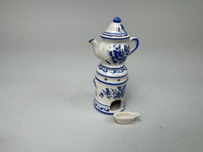 une petite théière bleue et blanche contenant une cuillère
