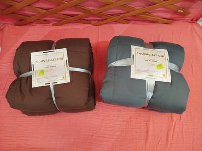 deux couvertures posées sur un lit recouvert d'une couverture rose