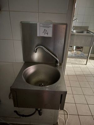 un évier au milieu d'une cuisine, sur lequel est accrochée une pancarte