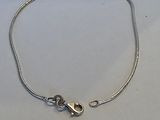 un bracelet à chaîne en argent avec un fermoir, posé sur une surface blanche
