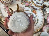 a person that is holding a plate with a bunch of cups and saucers