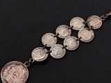 un gros plan d'un bracelet composé de pièces de monnaie posé sur une surface noire