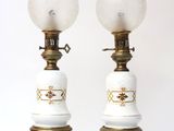pair of white and gold lamps with glass globes on them