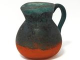 un vase bleu et orange posé sur une surface blanche