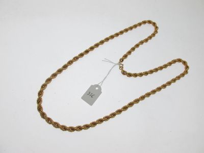 une chaîne en or à laquelle est accrochée une médaille, posée sur une surface blanche