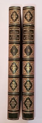 two old books are sitting on a white surface next to each other