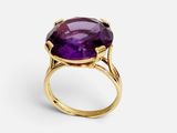 gros plan d'une bague en or avec une pierre violette