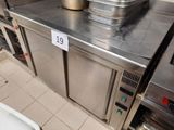un plan de travail en acier inoxydable sur lequel sont posés des casseroles et des poêles, dans une cuisine professionnelle