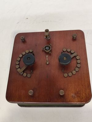 une boîte en bois ornée de boutons, posée sur une surface blanche