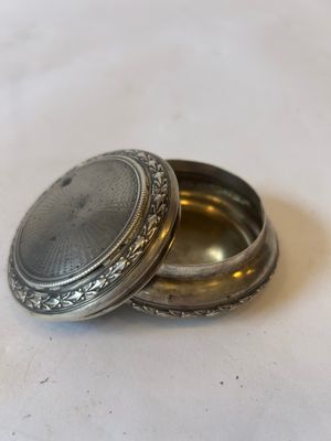 a small silver box with a silver lid on a table